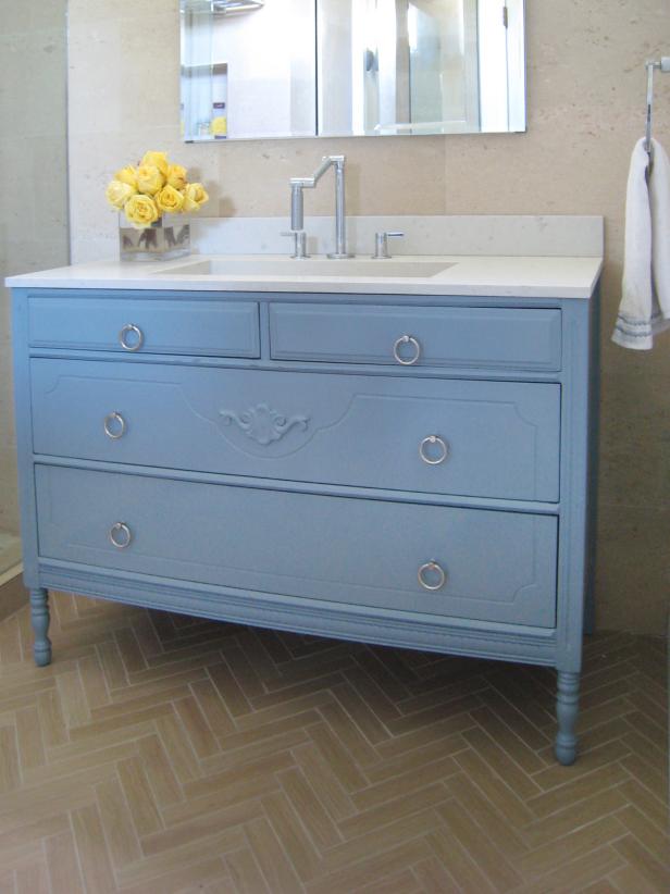 A vanity painted light blue with a modern bathroom faucet. This repurposed dresser is a great look