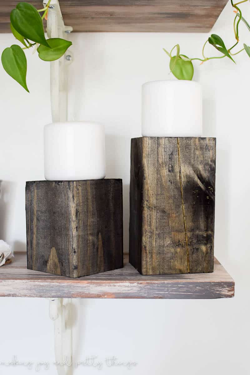 Wood post stained with dark wood stain holding white pillar candles on floating shelf