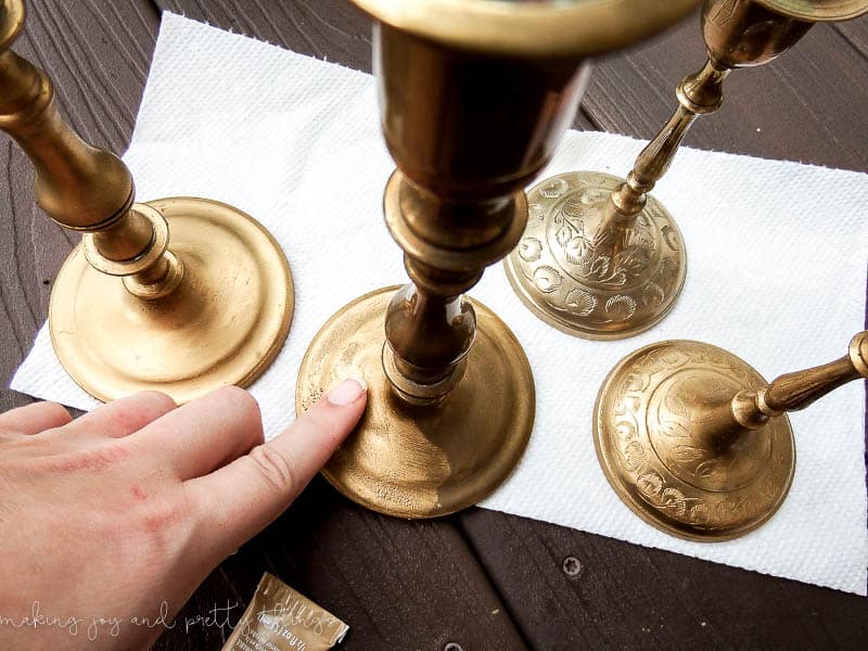 Use your fingers to apply the golf gilding wax finish to the base of the thrifted candleholders, and in just a few minutes, you have a stylish, elegant candleholder makeover.