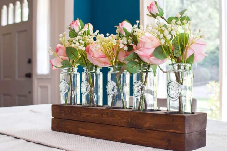 See how I used a scrap 2x4 board and transformed it into a simple wooden farmhouse style centerpiece using 5 blue glass vases.  Add in some beautiful silk roses and you have a gorgeous, easy centerpiece!