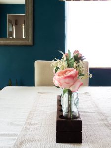 See how I used a scrap 2x4 board and transformed it into a simple wooden farmhouse style centerpiece using 5 blue glass vases.  Add in some beautiful silk roses and you have a gorgeous, easy centerpiece!