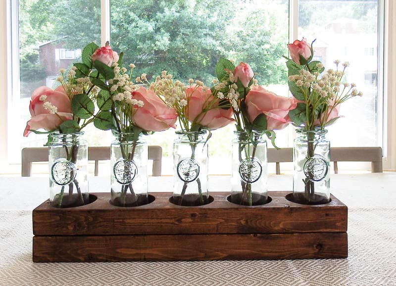 DIY wood centerpiece on a table in a dining room place in a way that shows off natural light and gives a nature feel 