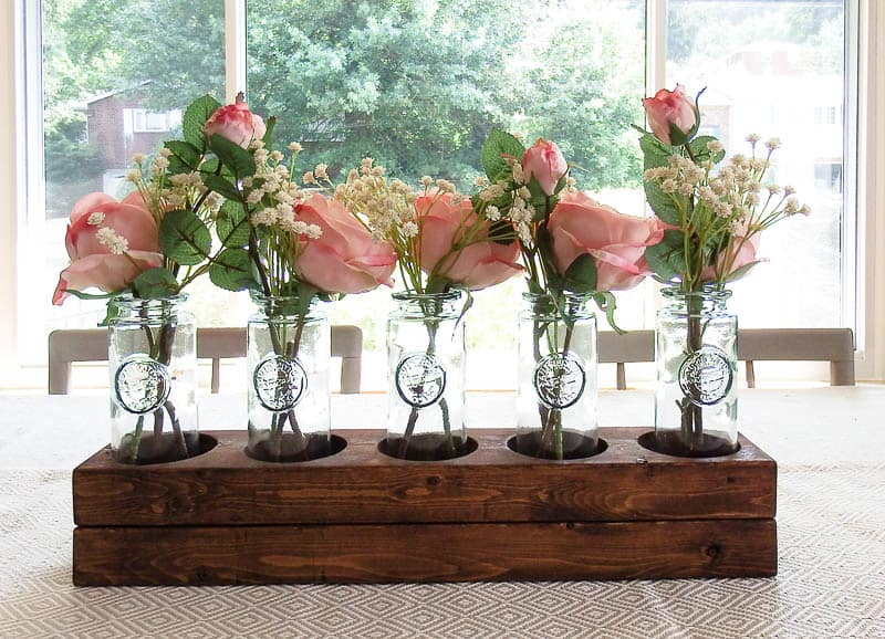 DIY wood centerpiece on a table in a dining room place in a way that shows off natural light and gives a nature feel