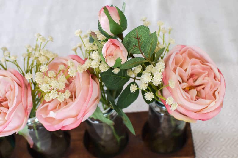 Close up of greenery and how the flowers accent off them that create a farmhouse style with a bottle idea