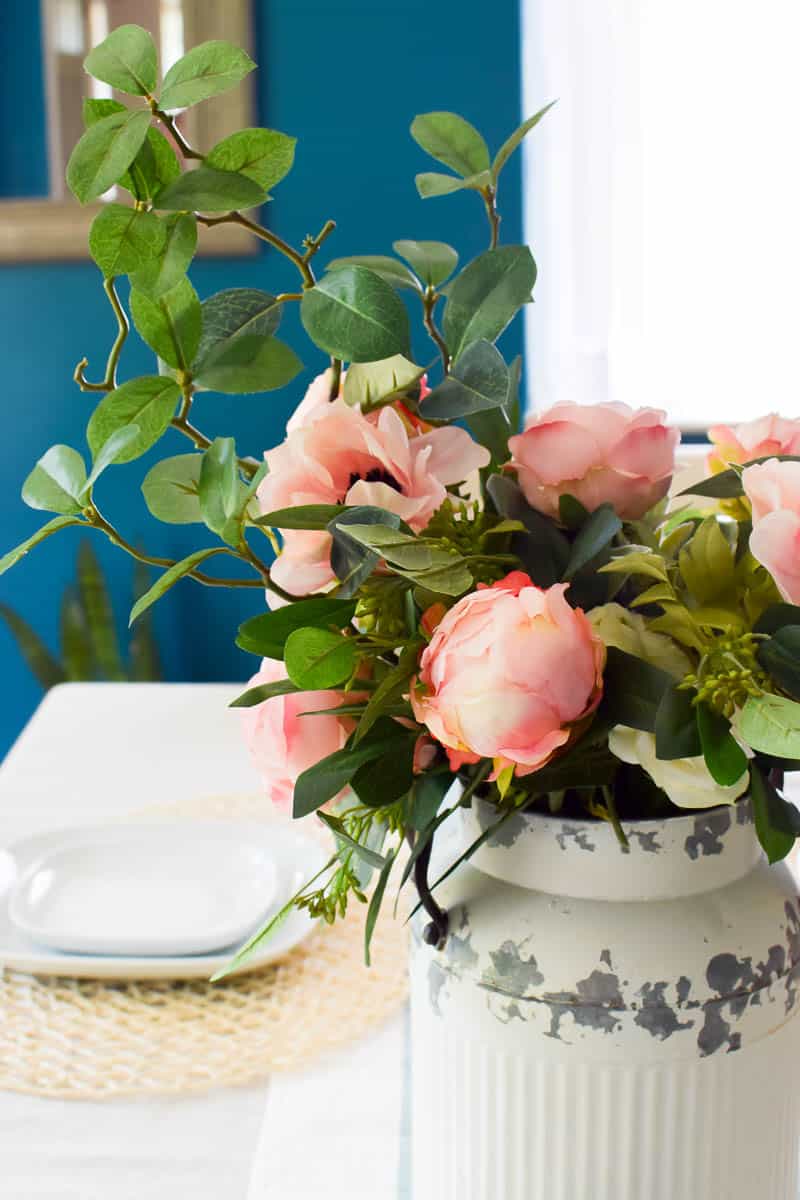 A vintage milk jug can really set up an entire room when you decorate it fully with floral accents and greenery 