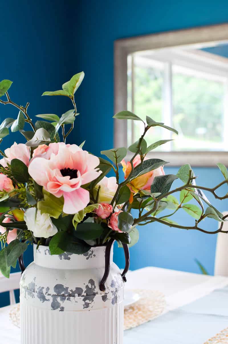 Close up of pink roses and other flowers in an old milk can on a dining table used at a focal piece