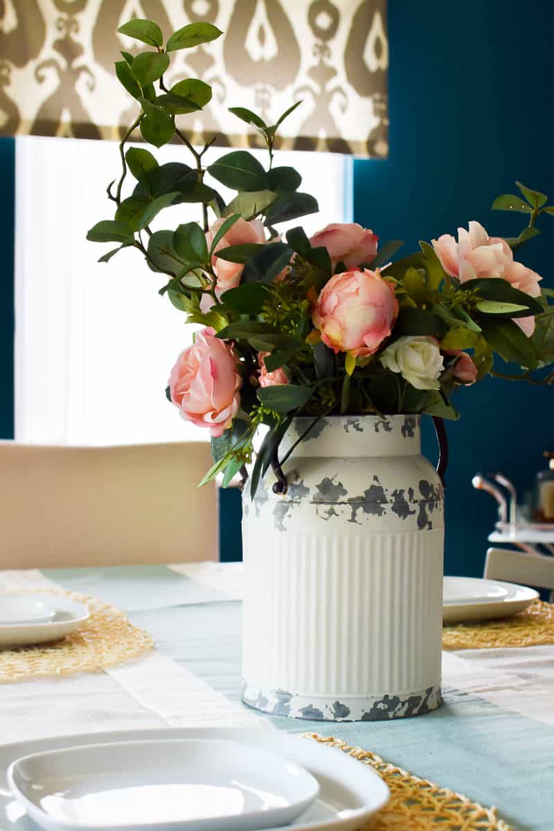 A past project using a vintage rustic milk can using faux flowers used as a farmhouse centerpiece for a dining room table