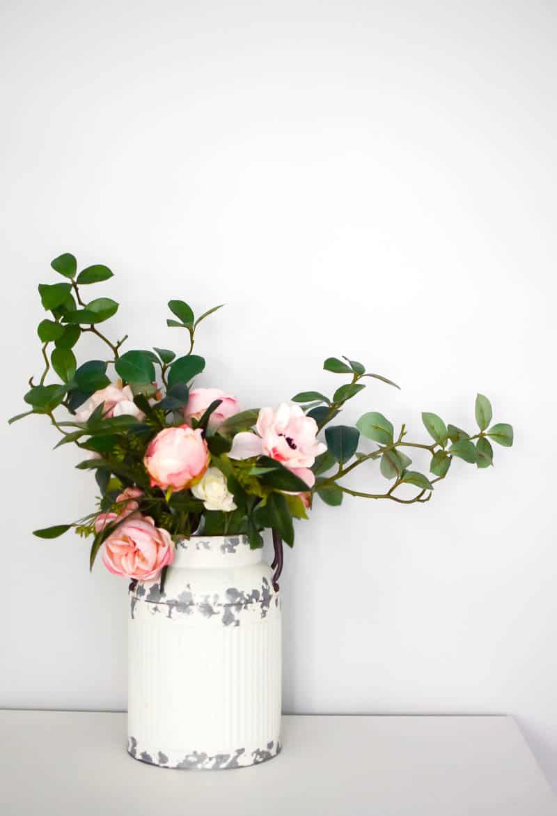 Simple farmhouse decor using floral touches and greenery in an old vintage milk can