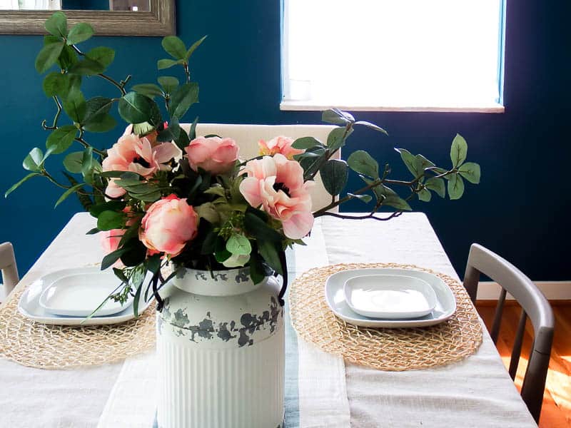Set dining room table with chargers that shows off just how amazing this farmhouse floral arrangement is