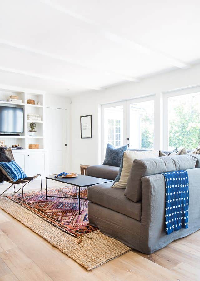 A vintage-patterned southwest sisal rug lies under a couch in the living room on top of a neutral sisal rug, giving the room a perfect layered rug look