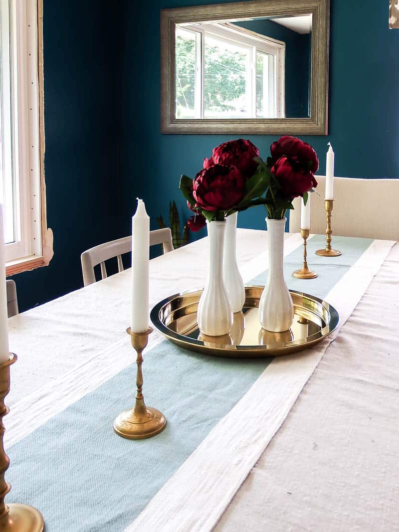 Red roses in a thrift store vase set of 3 on a gold dish charger used as a simple floral centerpiece on a dining room table.