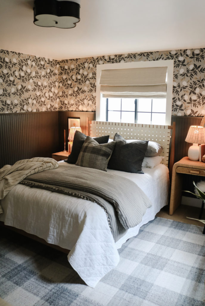 Moody bedroom with floral patterned wallpaper over a black-painted beadboard wall treatment