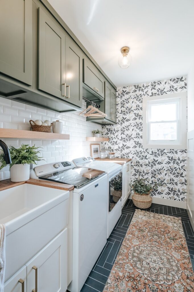 If you're looking for laundry room wallpaper ideas, you'll love this floral wallpaper accent wall. It is the ultimate finishing touch, seamlessly complementing green upper and white cabinets below in a laundry room.