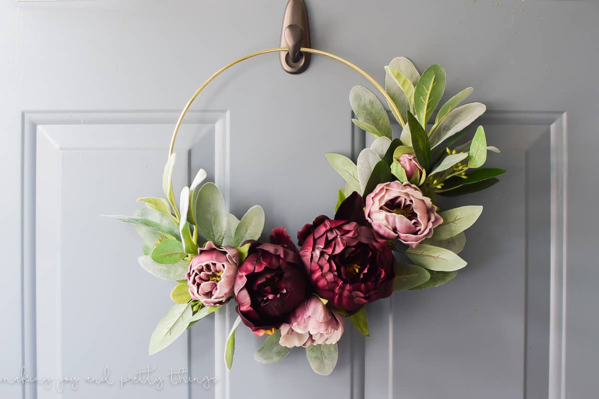 Hanging the gold ring wreath on an exterior door using a glue hook 