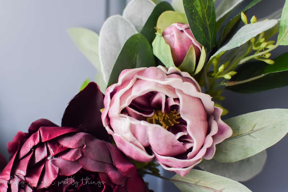 Nice color contrasts like these pink and maroon flowers really show off on this gold ring wreath