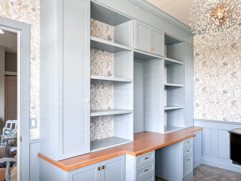 Toned-down color scheme in home office with light blue built-ins and a matching wallpaper on the walls