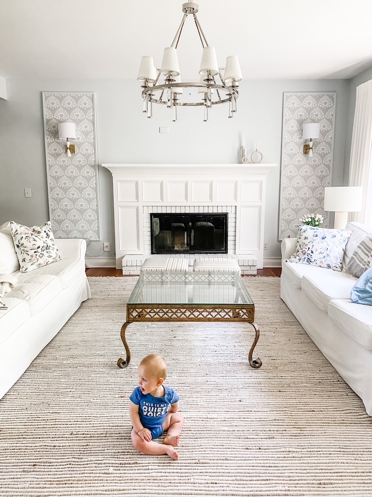 A photo of a living room with wall paper framed and a fireplace, as well as an image of the baby.