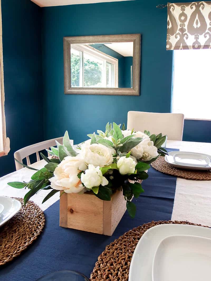 Lovely farmhouse floral arrangement on a dining room table that shows off flowers and greenery