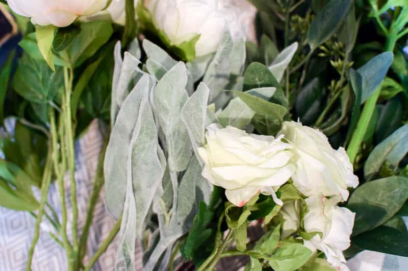 Various greenery and flowers used to make a diy wooden box centerpiece for a dining room table