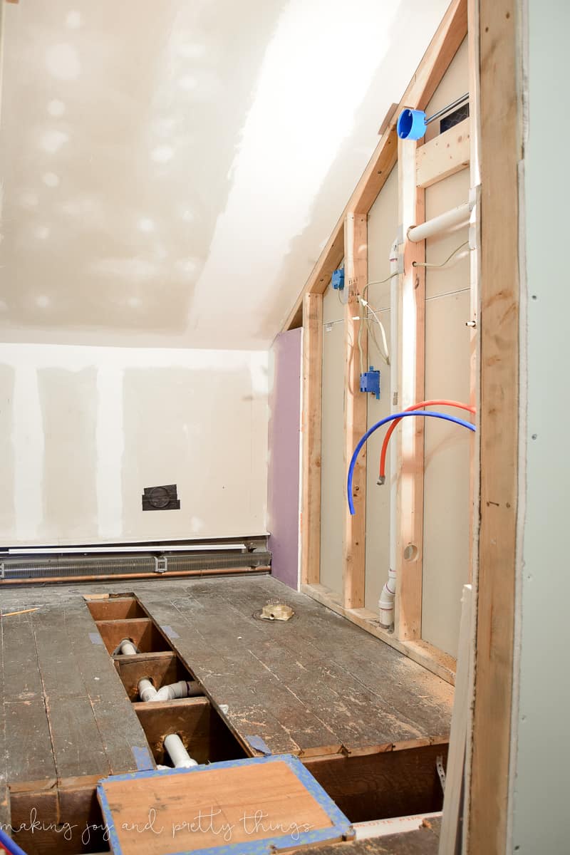 Our master bathroom, mid-renovation: subflooring is removed, exposing plumping pipes, exposed dry wall, pipes, tubes, and dust everywhere.