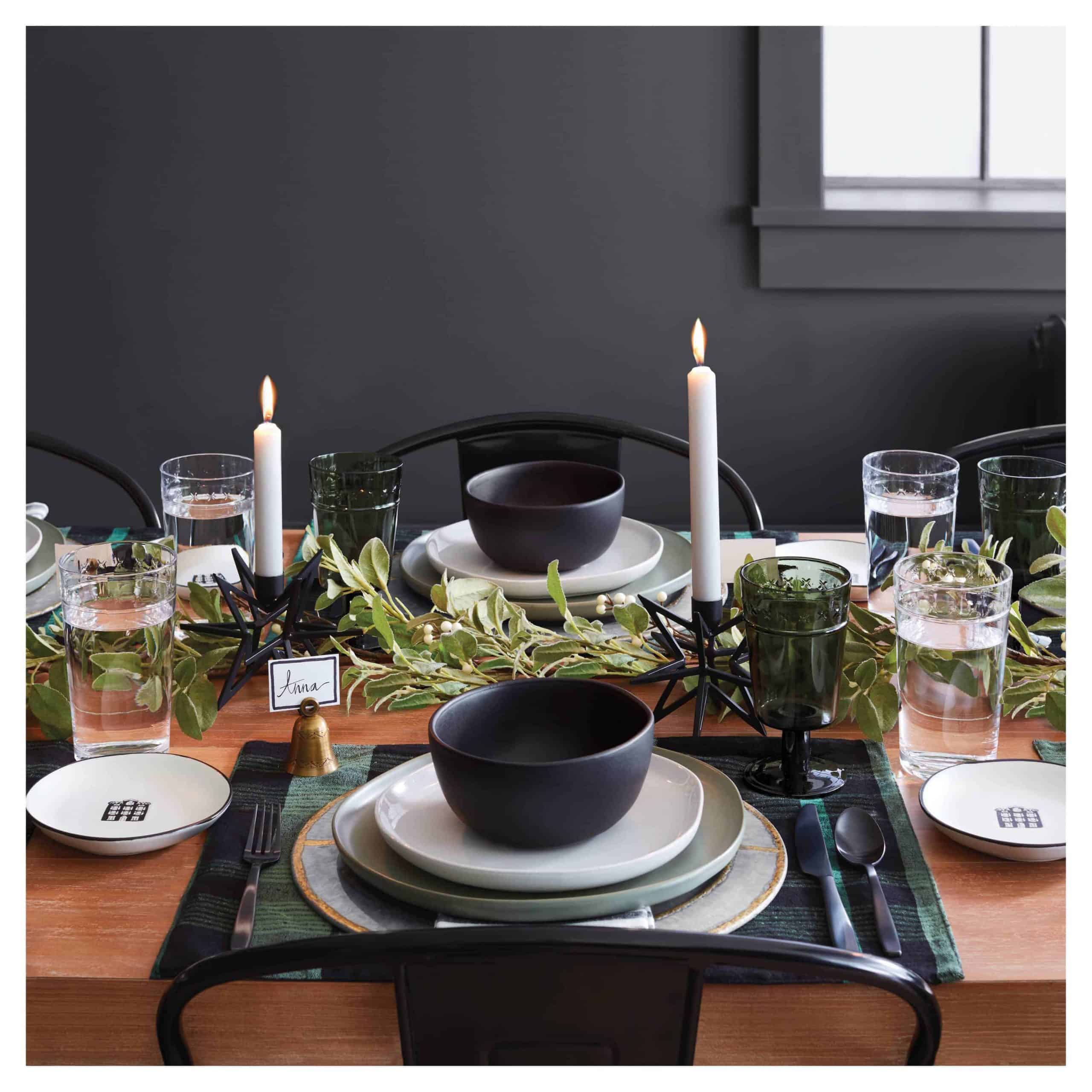 A photo of a table set with a candle and utensils in a black theme.