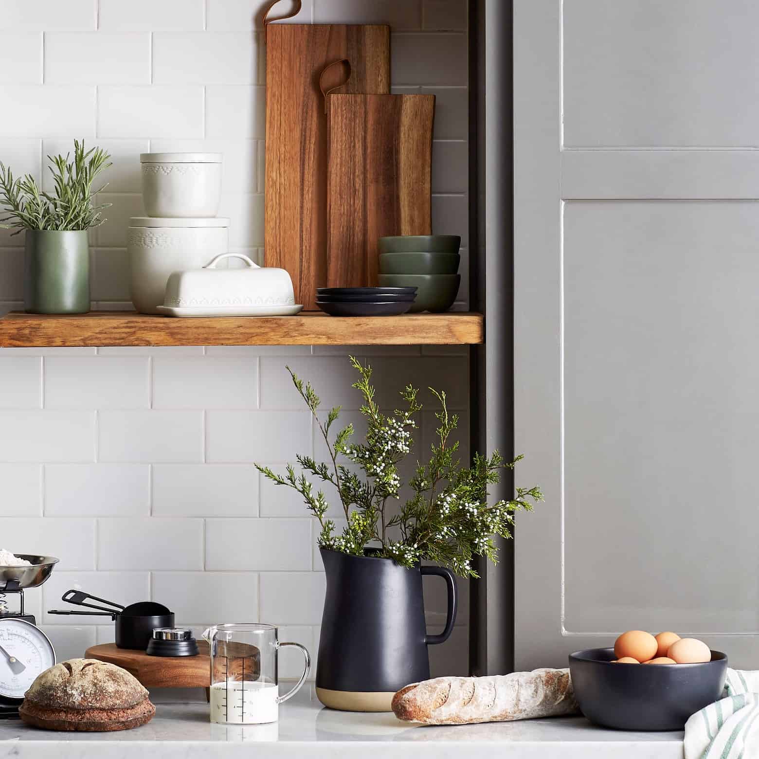 A kitchen with some utensils, bread, and plant decor.