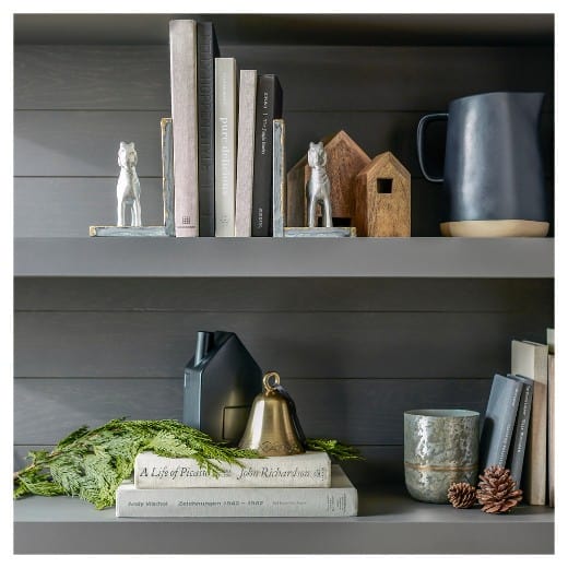 A photo of a bookshelf with grey shelves, books, and decorations.