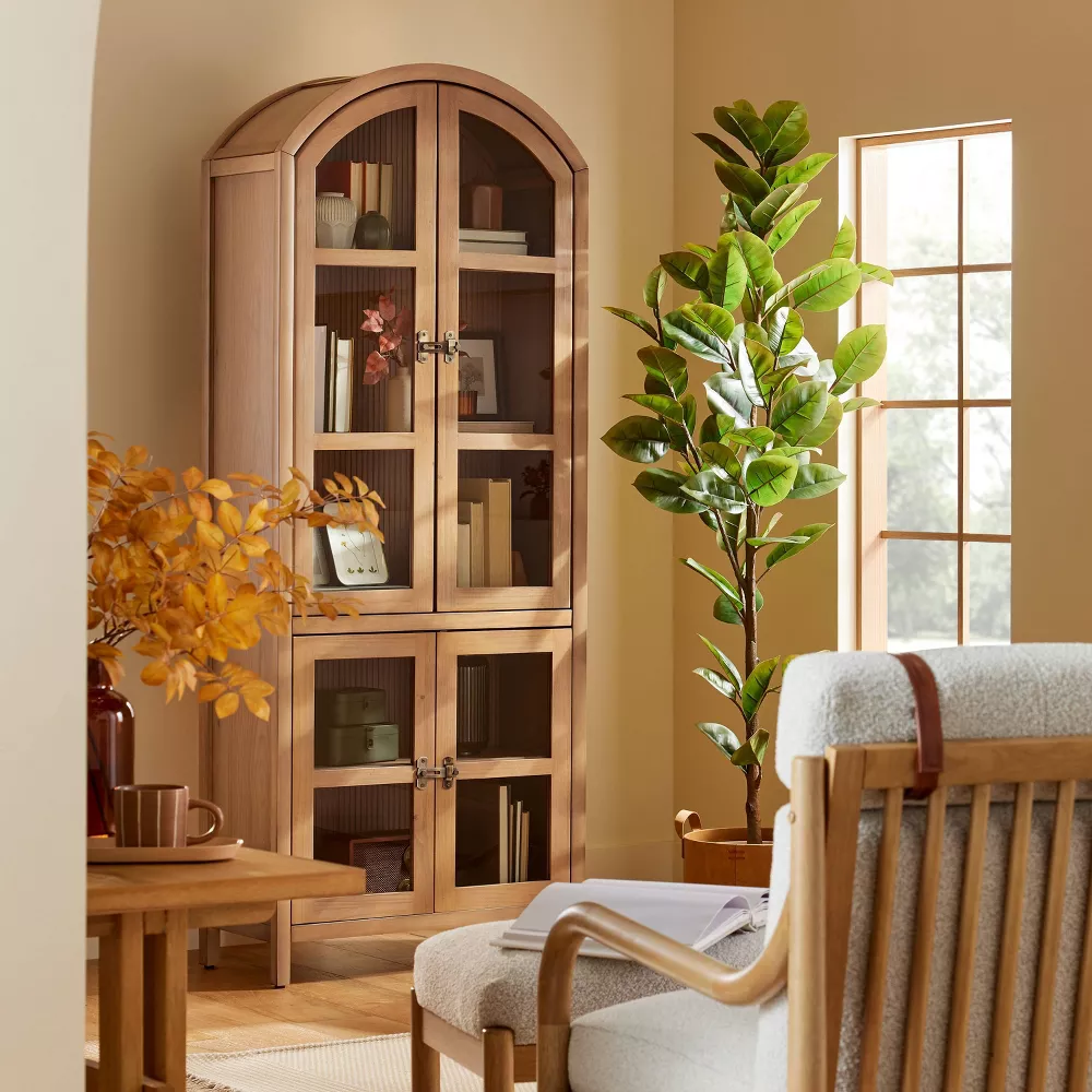 A farmhouse-style living room photo with a cabinet, armchair, table, and indoor plant.