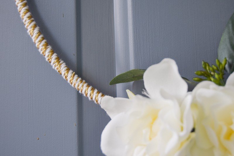 Close up photo of the gold and white twine used as a base to attach flowers and greenery to the gold macrame ring