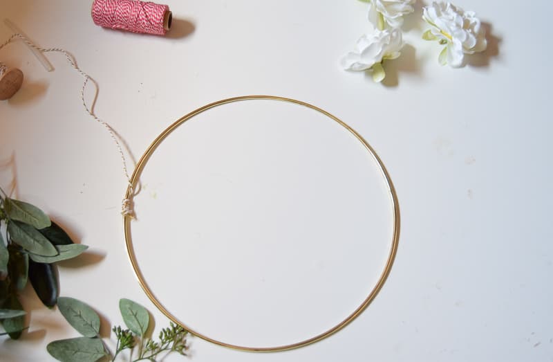 Start the winter wreath for front door after christmas by gluing the twine around the gold hoop