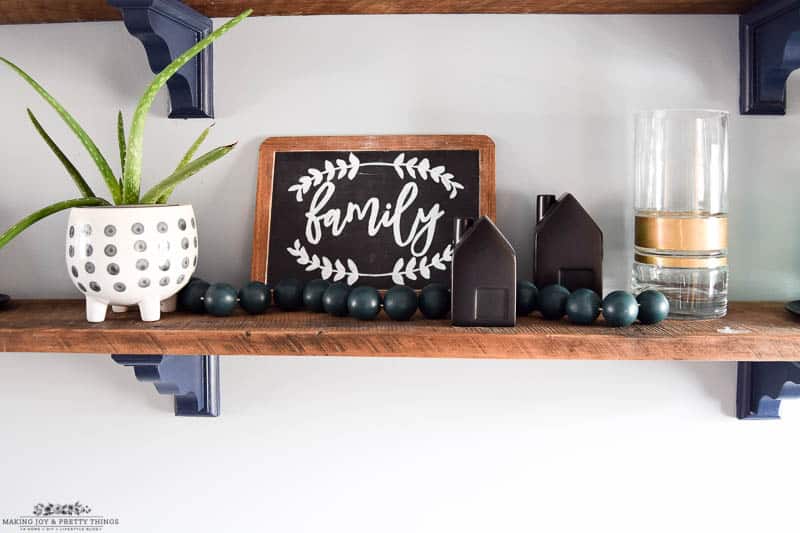 Handing the DIY wooden ball garland on a rustic shelf with chalkboard and other various decor to balance out the design