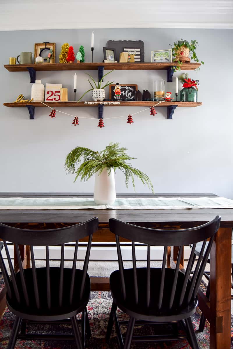 Overall view of a dining room that has been decorated for Christmas using greenery and various kinds of other decor items