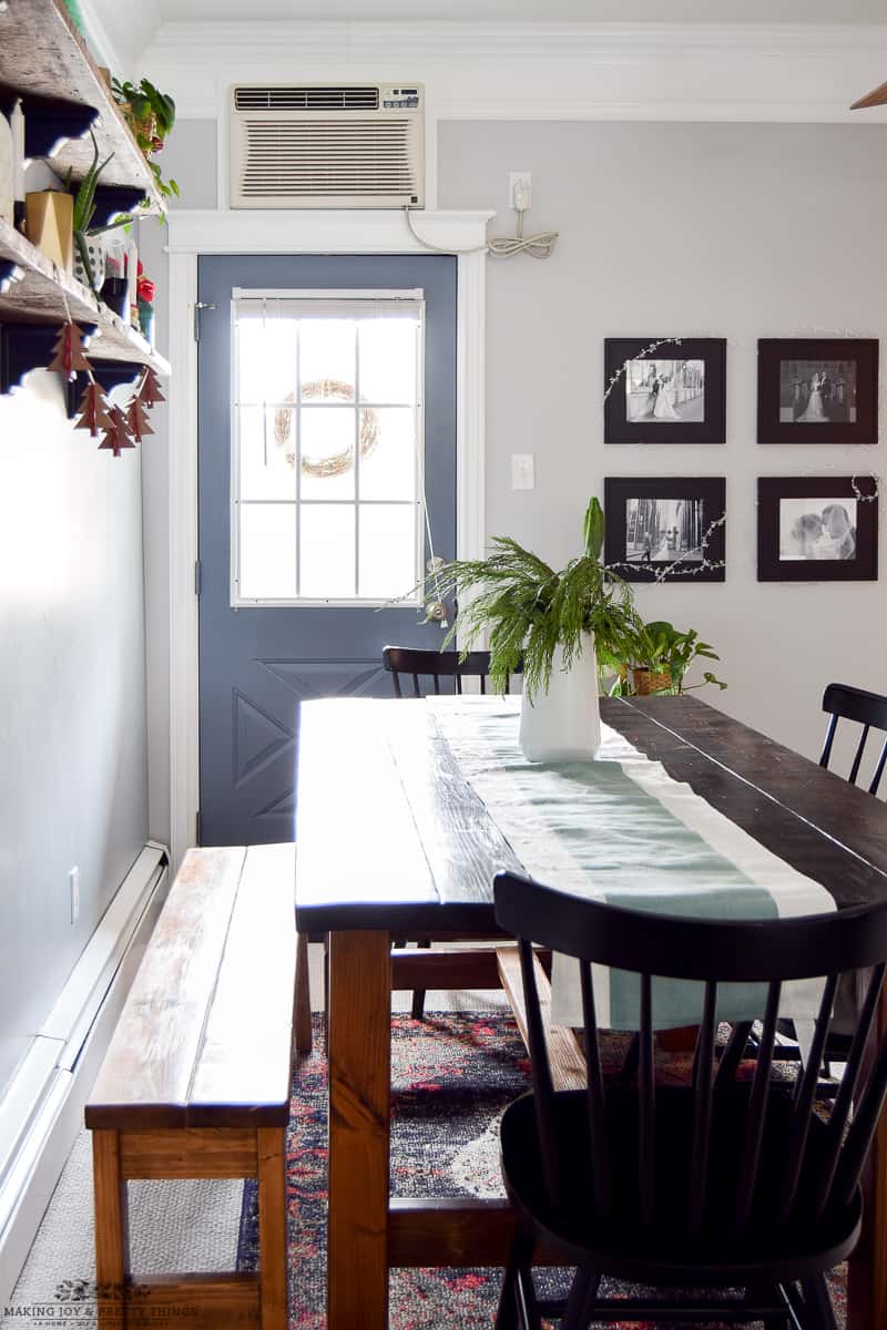 Subtle dining room table decorated for Christmas in a minimalistic fashion with like greens and neutral table runners