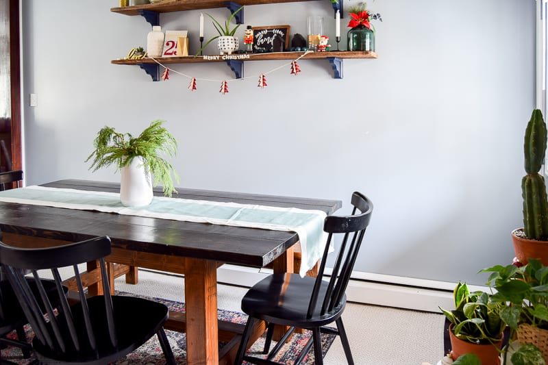 Fresh cedar clippings in a vase on a table runner used as a center piece for a dining room table for Christmas