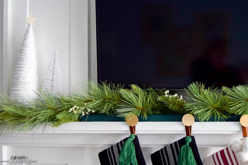 A Christmas garland over a DIY stocking holder sets up a mantel and provides a nice focal point for a living room
