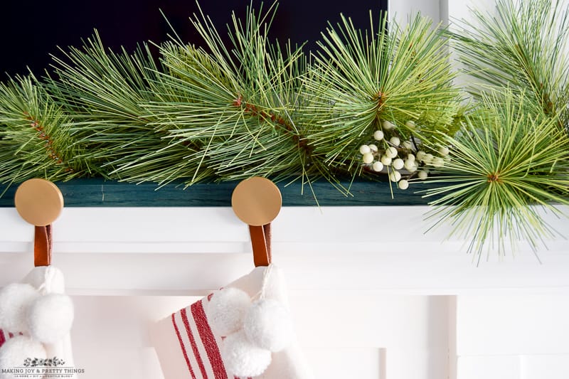 Close up view of a Christmas garland and brass knobs with a modern mantel look 