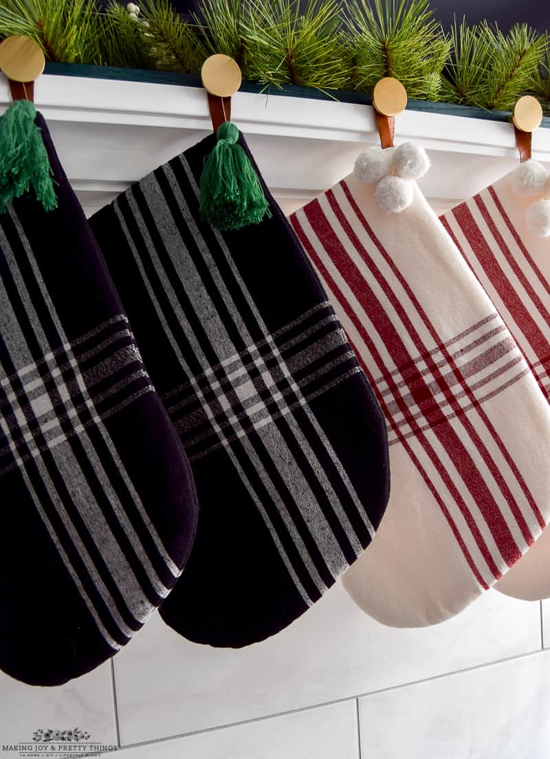 Plaid colored stocking sets for family hung on a mantel with a DIY stocking holder with brass knobs