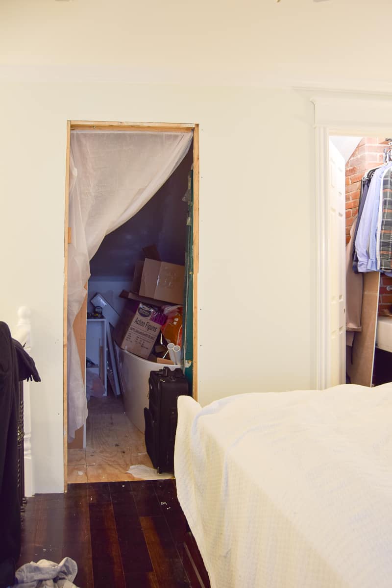 The entrance to the master bathroom before it's makeover: the doorway doesn't have a frame, and the bathroom is packed with boxes of clutter.