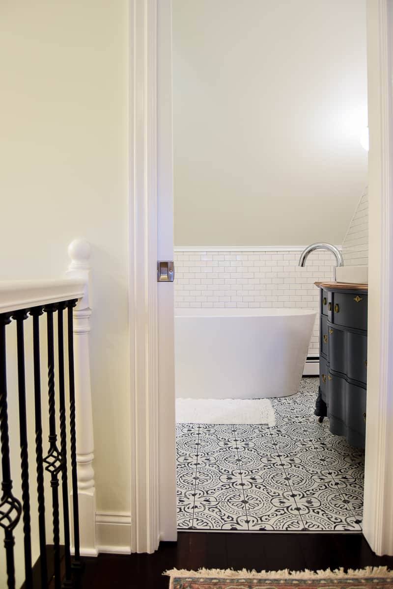 A peak into the modern vintage master bathroom from the hallway shows the corner of the bathtub and vanity.