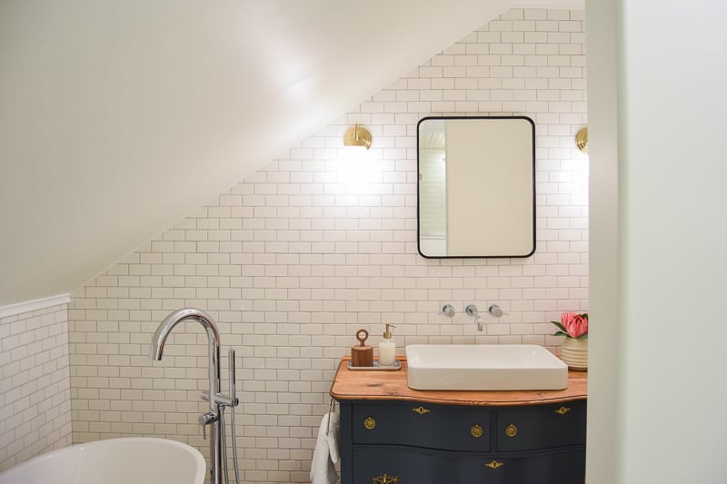 The slanted ceilings of our master bathroom over the tub and vanity, and white tiled walls.