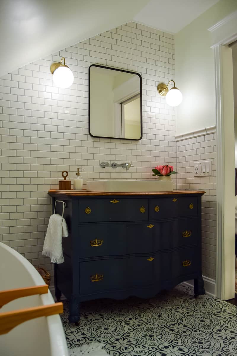 A full look at the vintage dresser we converted into a bathroom vanity - painted deep forest green, with two drawers, gold handles, and an inlayed white porcelain sink.
