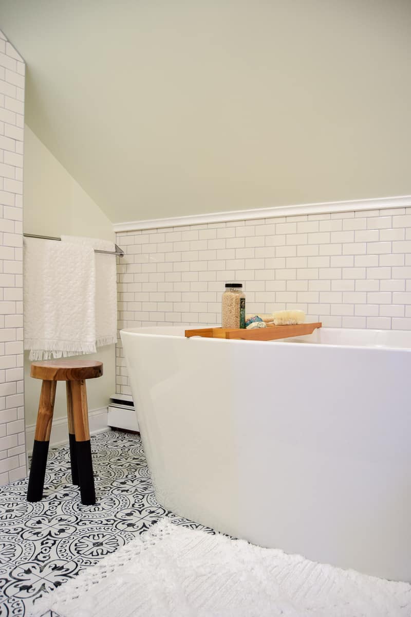 Our deep soaking bathtub, bath tray with bath salts, a sitting stool, and wall-mounted towel rack.