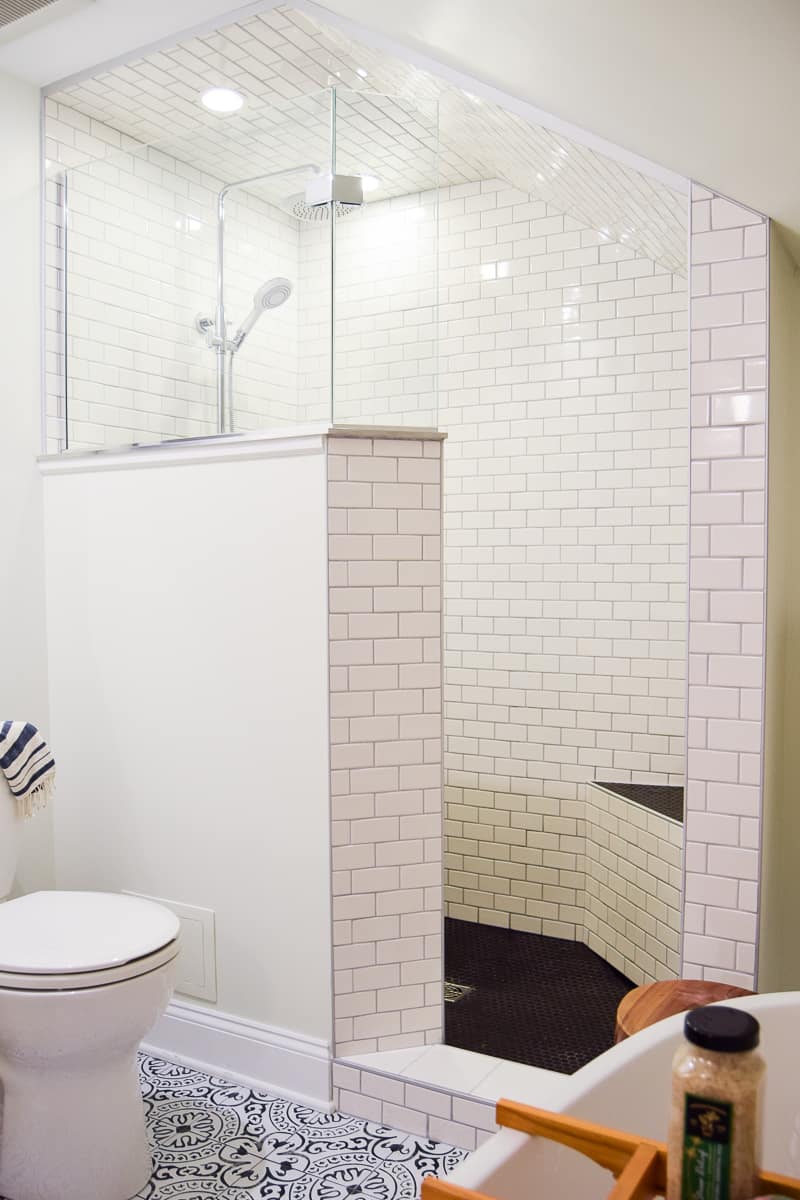 A full walk-in shower with partial enclosure, glass shower windows, subway tiled walls, and a rainfall shower head.