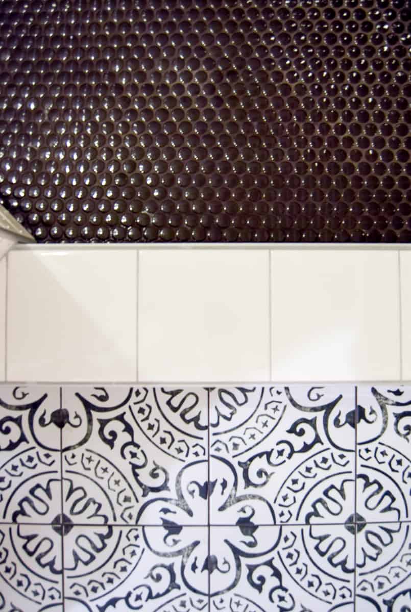 Comparing the busy design on the black and white floor tiles to the simple, clean white subway shower tiles in our updated modern vintage bathroom makeover.