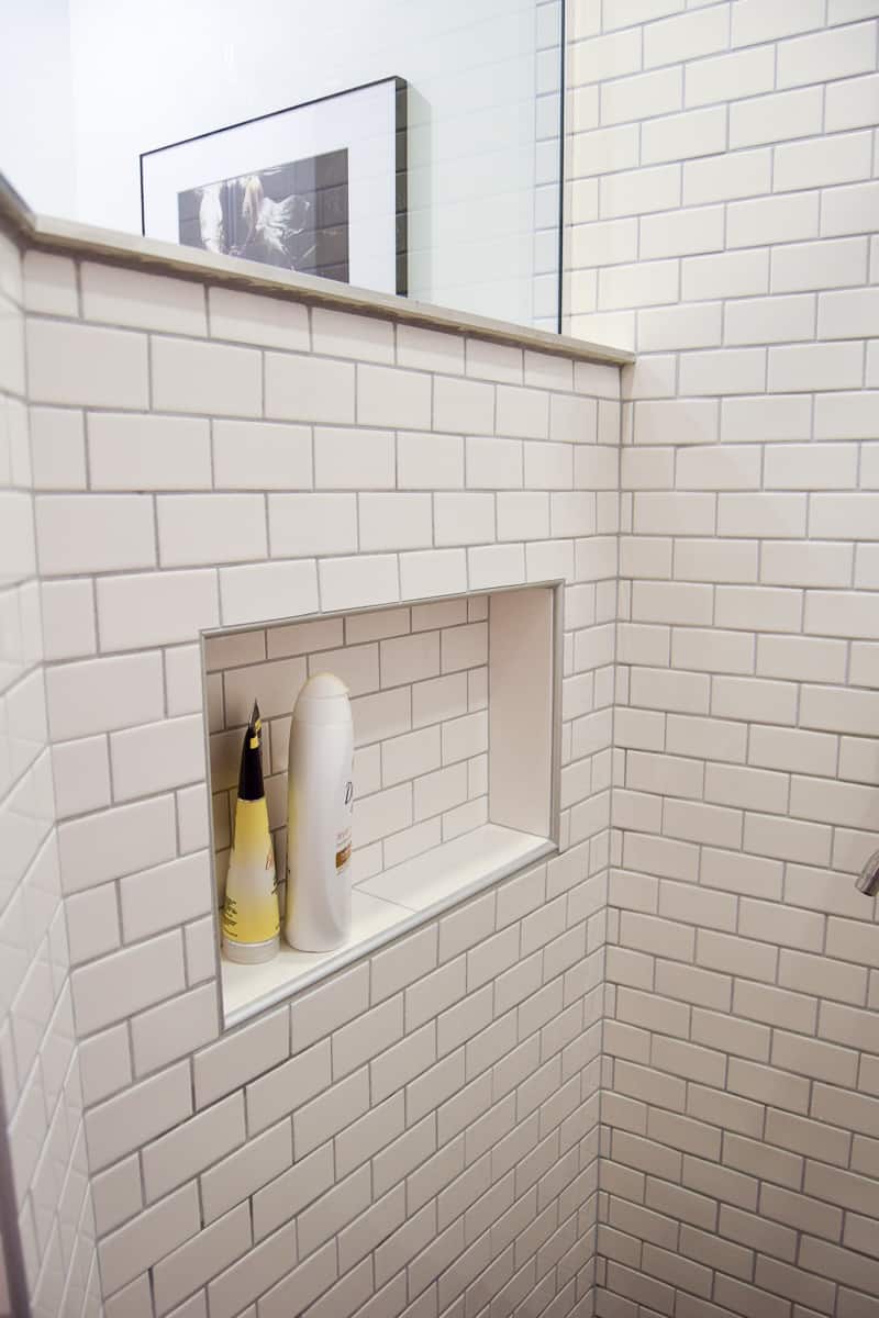 We installed a convenient shower nook inside the half-wall of the walk-in shower, and tiled it with matching white subway tile.