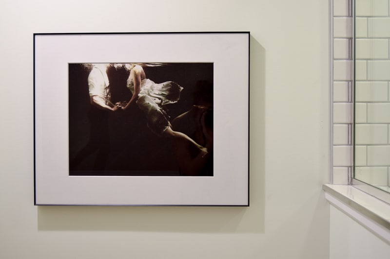 A closer look at the framed photo hanging on the wall in the toilet nook in our modern vintage bathroom - a man and a woman swimming in water, holding hands.