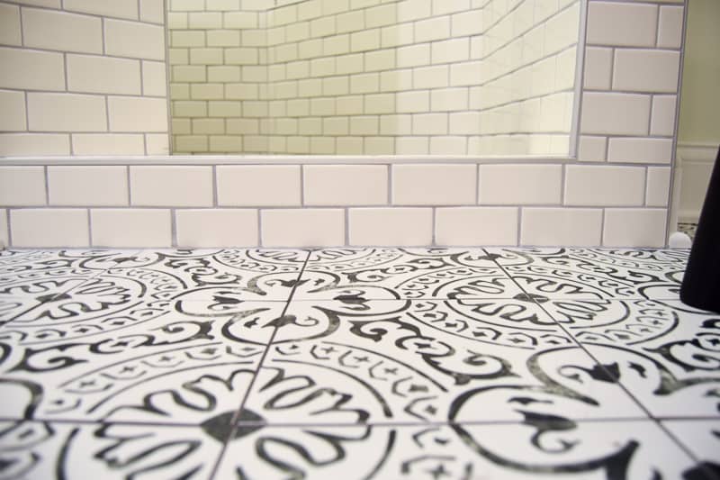 A close up look at the balance of the busy patterned black and white floor tiles and the clean and simple white subway tiles.