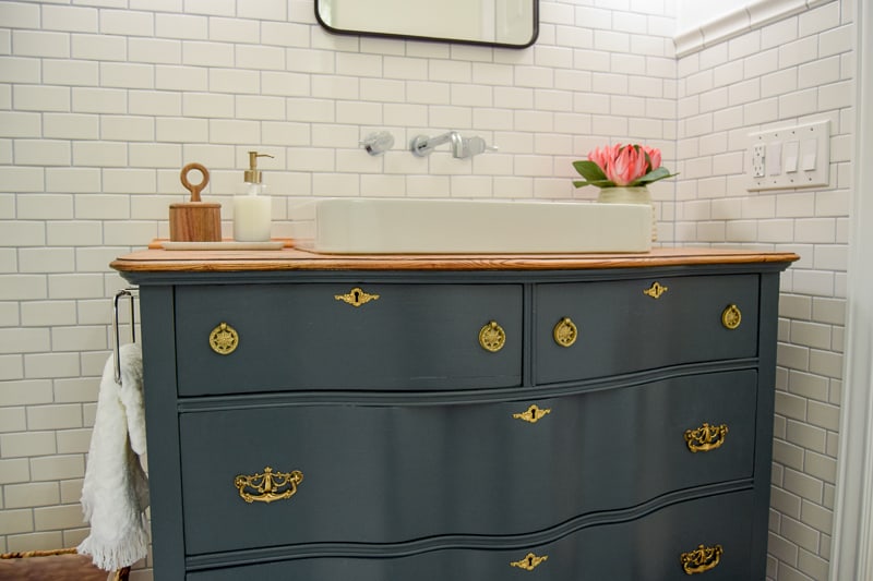 The vintage dresser we picked for our modern vintage bathroom makeover has a gorgeous shape, drawers, and wood surface with a inlay white porcelain sink.