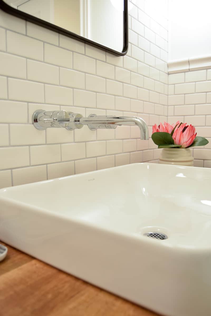 I love the modern look of the wall-mounted faucet over the sleek white porcelain sink in our vintage modern bathroom.