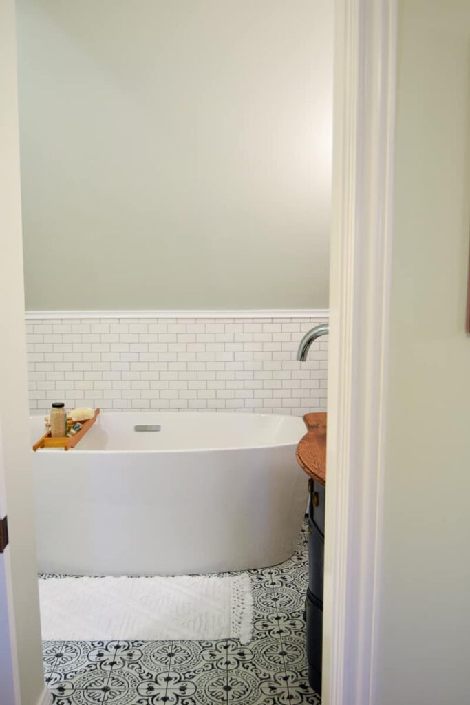 A modern bathroom with a white bathtub with a wall covered in subway tile and painted with Simply White by BM on the wall